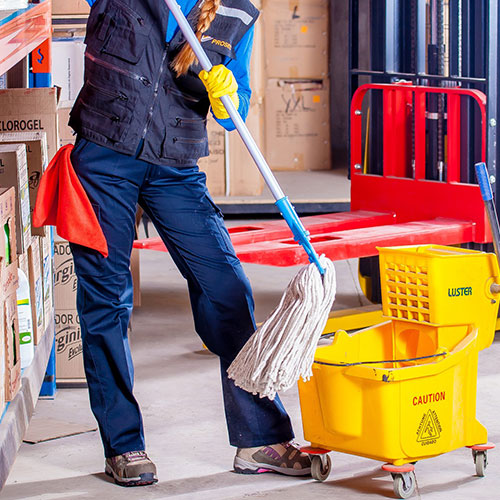 Person mopping a floor with industrial mop and container